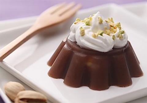 En una cacerola, hervir las castañas con agua azucarada durante 5 minutos. Sacar las castañas del agua. Añadir la pasta de judías rojas al agua azucarada y hervirla junto con la gelatina a fuego lento hasta que la gelatina se derrita. Verter la mezcla en un molde de budín y añadir también las castañas en el molde. Poner el molde en la nevera hasta que cuaje. Desmoldar el pudin y volcarlo en un plato. Cubrir con nata montada y granos de pistacho picados.