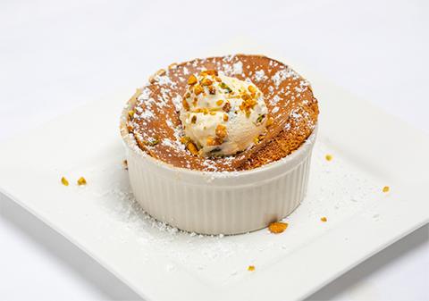 Para la Crème Brûlée de pistacho y cardamomo Precalentar el horno a 160o C. En un cazo, batIR la nata espesa, la pasta de pistacho, el cardamomo entero, ½ taza del azúcar y el agua de rosas. Poner el cazo a fuego lento, llevar a ebullición y batir hasta que esté completamente suave. No hervir. Retirar las vainas de cardamomo e incorporar los pistachos tostados a la mezcla de nata. Pasar la mezcla por un colador fino a un bol grande. Batir la ½ taza de azúcar restante y las yemas de huevo. Añadir 1/3 de taza